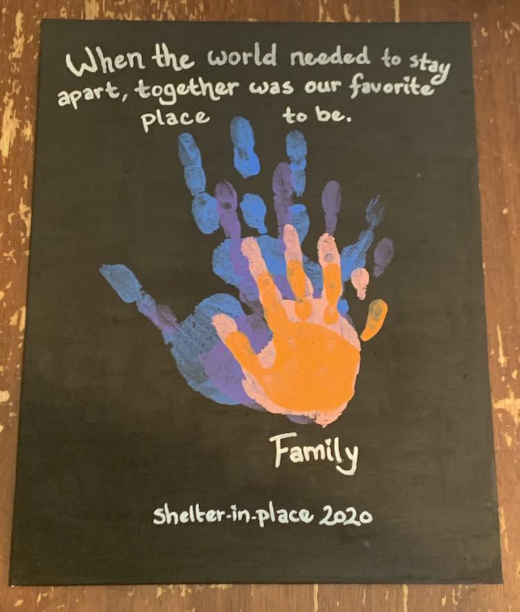 The black canvas with the centered stacked hands reads "When the world needed to stay apart, together was our favorite place to be." above the hands while below it reads, over two lines, "Last Name Family" followed by "shelter-in-place 2020".