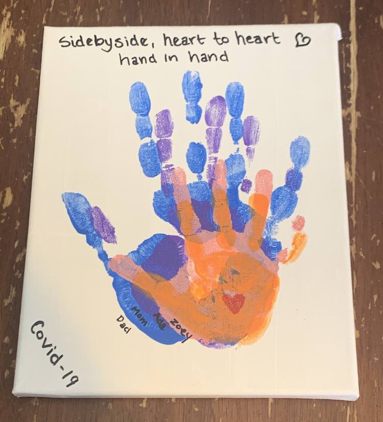 The small white canvas has all four hands stacked in the center with the lower right side of the palm lining up so the fingers, mostly, stand out. From largest to smallest it goes blue, purple, pink, and orange with a small red heart in the center of the orange palm. The names are written outside each handprint on the lower left side in black with an oil-based paint pen like I used with the other letters.