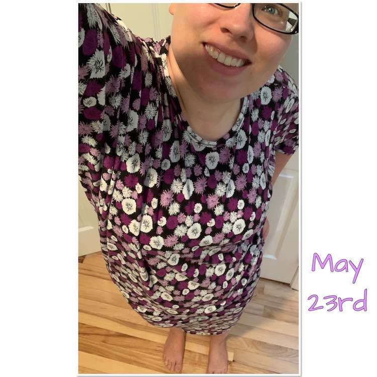 Selfie view, back to one eye, of a purple and white flowered dress. The neck is a crew neck with a binding and the sleeves end at the elbows. The dress reaches to my knees but it's hard to see the length from this angle. The shirt has a large batwing so you can see extra fabric draping at the armpit of the arm holding the phone. 