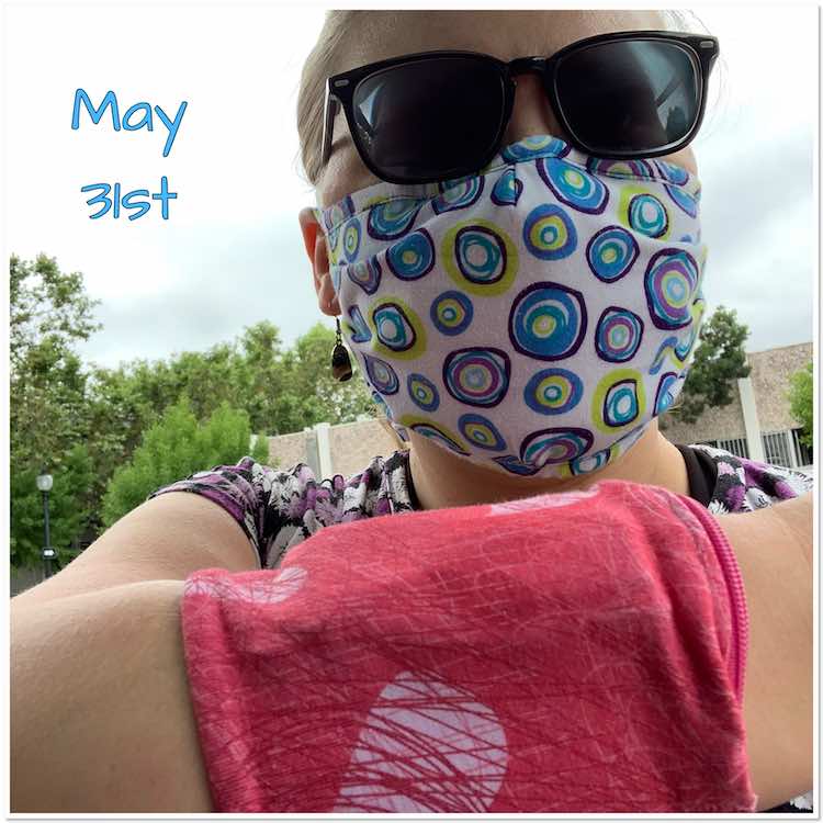 Selfie outside rather than most of the other indoor ones. Here I'm wearing sunglasses, a mask, and a cuff on my visible arm. Behind it all you see a hint of a previously work purple flowered Dynamite shirt. The mask is white with colored circles and you can see the bias tape along the top is made of the same fabric. The cuff is pink with scribbled hearts in white and lighter and darker pink. 