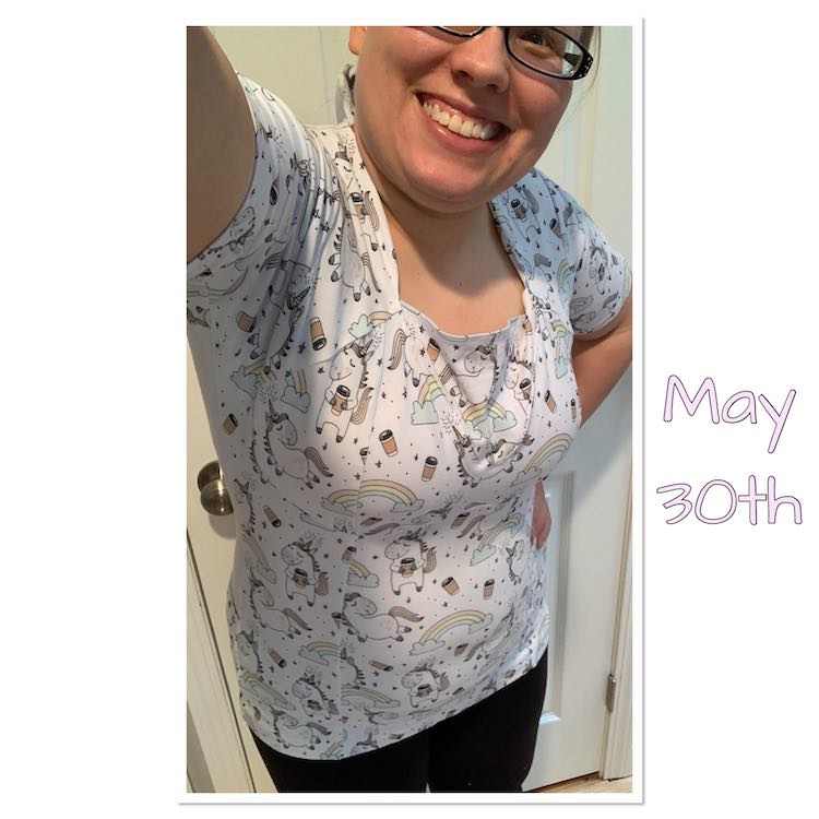 Selfie view showing a single eye down to the bottom of my shirt. The shirt is white with many rainbows, coffee cups, small hearts, and unicorns on it. If you look closely you can see the seam lines vertically over my stomach and showing the bra cups have been sewn together. 