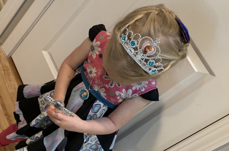 Front view of Zoey looking down to show the crown and top of her head. In her hands is the wand, hard to see, and around her neck is the new Anna necklace. 