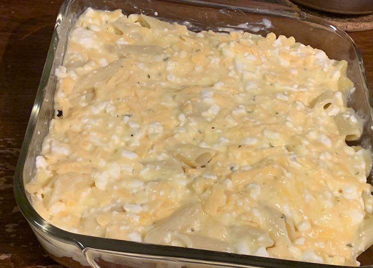 The 9 inch square clear casserole is now about two thirds filled. The top is the yellow, white, and orange mixture with beige penne pasta poking through. There's still the odd open space in the pasta layer but not many. 
