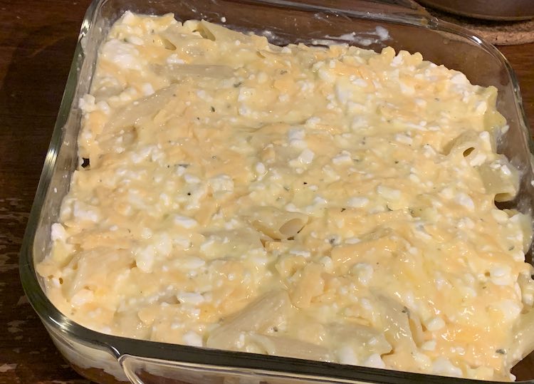 The 9 inch square clear casserole is now about two thirds filled. The top is the yellow, white, and orange mixture with beige penne pasta poking through. There's still the odd open space in the pasta layer but not many.