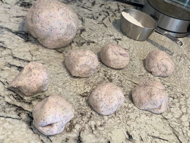 Image shows my countertop with seven small balls of sparkly white-ish playdough and one large ball. Behind them sits a metal measuring cup with some flour and my electric kettle. 