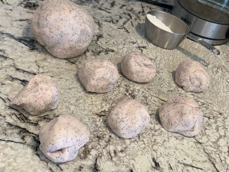Image shows my countertop with seven small balls of sparkly white-ish playdough and one large ball. Behind them sits a metal measuring cup with some flour and my electric kettle.