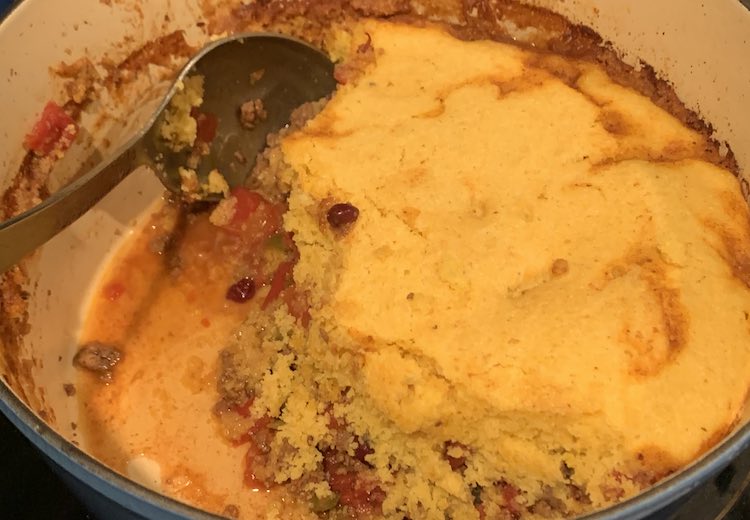 Overhead view of the dutch oven after it came out of the oven and I had served some of it. You can see the chili peaking from underneath the cornbread layer around the outside. 