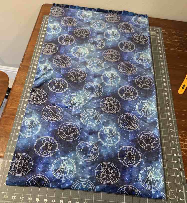 The fabric is folded in half lengthwise and then folded the other way so it mostly fits on the 36 inch long cutting mat making it easier to cut in half without measuring the fabric.