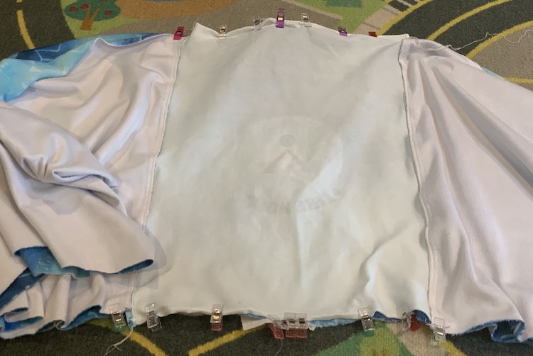 The fabric is laid out on the car mat with the left and right side of the pillow cover going off photo although the left side is folded or rolled up so you can see more of it. In the center the panel, and zippered coordinate underneath, is laid out flat and clipped along the top and bottom. 