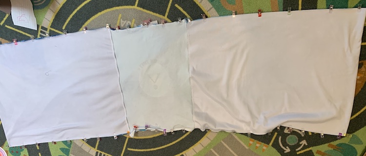 The pillow cover is laid out, mostly, flat and clipped along the top and bottom. The pillow goes a bit off screen on the right and left but you can see most of it from the reversed side as it's inside out. The paneled side is showing with the zipper hidden underneath.