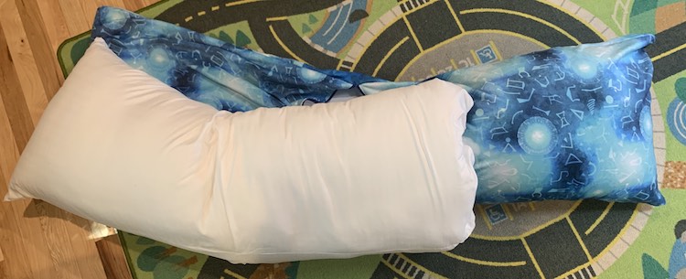 Closeup of the two pillows, sewn together, laid overtop of the pllow cover. The third pillow is inside the end of the pillow cover so you can see they are almost the same length, just a bit long for the pillow, compared to the cover. 
