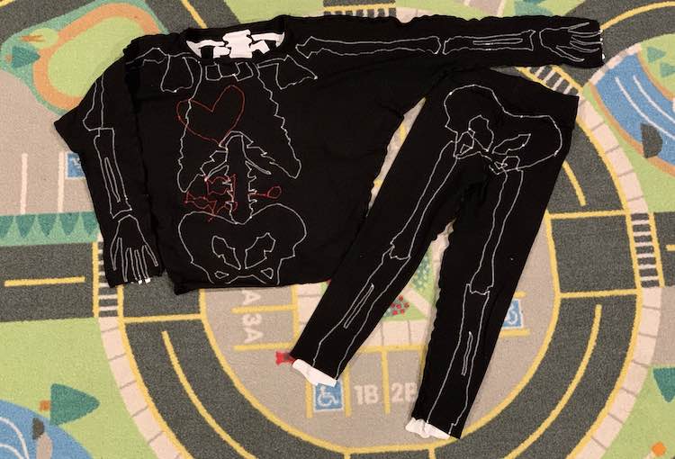 Image shows both garments inside out so you can see the outlined bones, heart, and candy. The shirt is beside the pants so the image is in landscape mode. You can easily tell the difference between the bones and the candy/heart as they used different thread. The bones are outlined in white zigzag stitches while the candy and heart used red. 