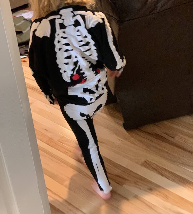 The back of Ada is shown while she skeleton walks away from the camera towards the living room. 