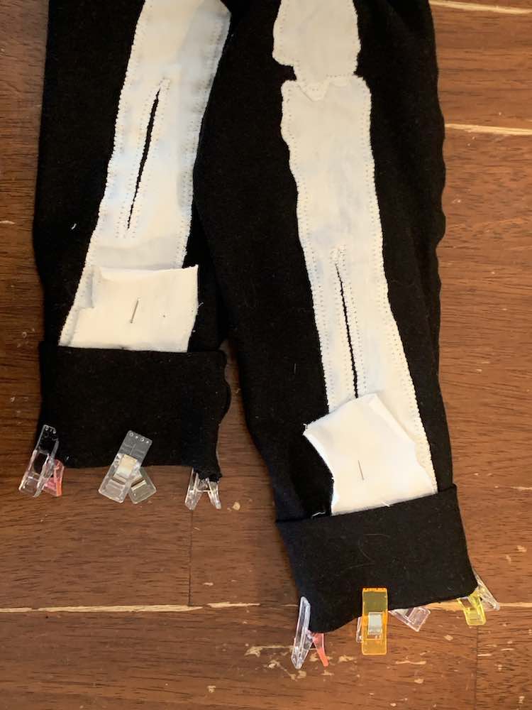 Image shows a closeup of the bottom of the pants with the white bones folded up and pinned in place. Hiding the bone fold is the cuff clipped in place. 