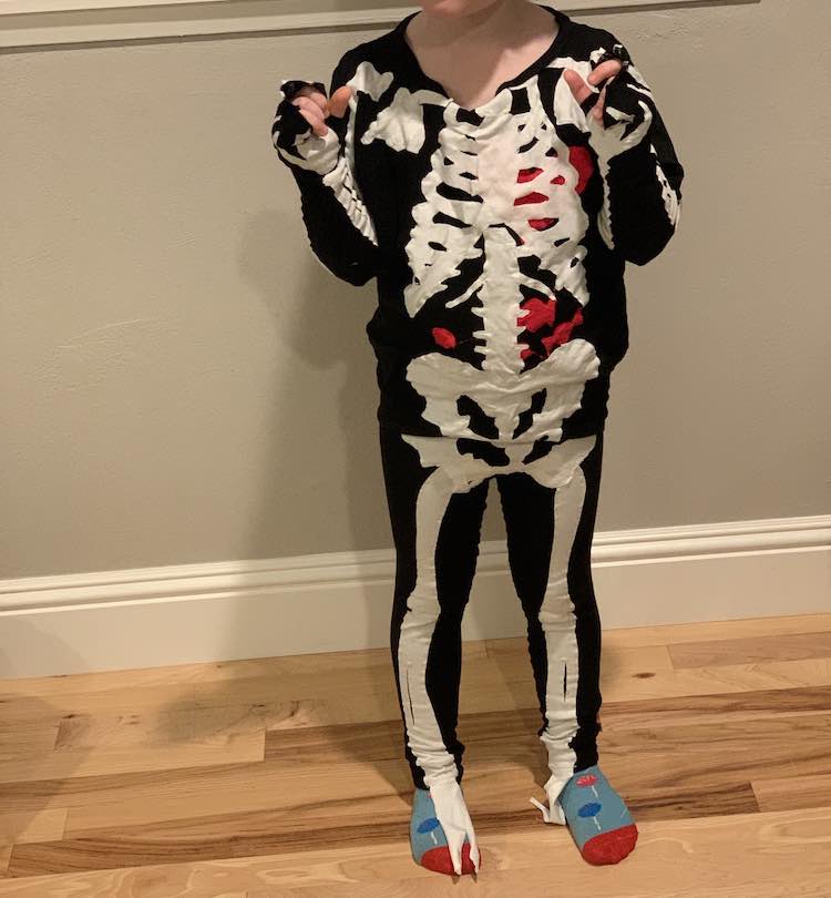 The image shows Ada from her neck down dressed as a skeleton with candy socks on to match the candy in her skeleton's stomach. Her arms are folded up as she wears the sleeves over her hands. 