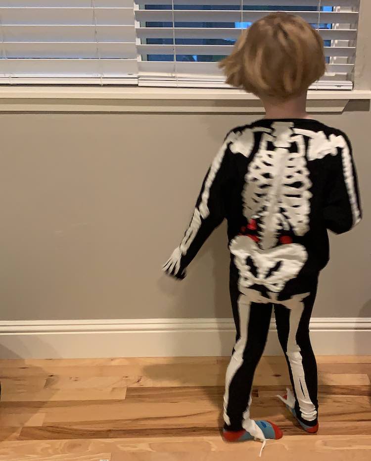 The back of the skeleton is facing the camera as she spins in the costume. 