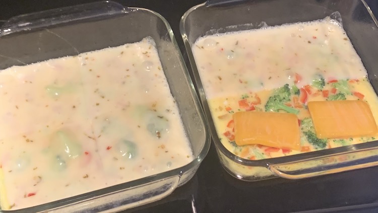 View of the two casserole dishes freshly taken from the oven and sitting on the stove. The left, slightly cut off, dish has white melted cheese with the odd broccoli bump showing. The right pan is half coated in the white pepper jack cheese while the half closest to you has two partially melted orange squares of cheddar cheese. 
