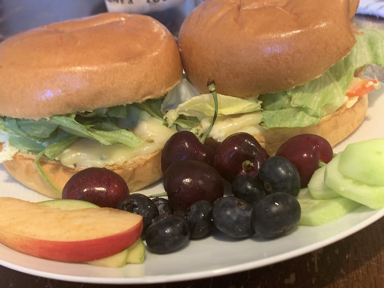 Side view of the plate. Up close you can see the cucumber and fruit while behind that you can see the side view of the egg bun-wiches.