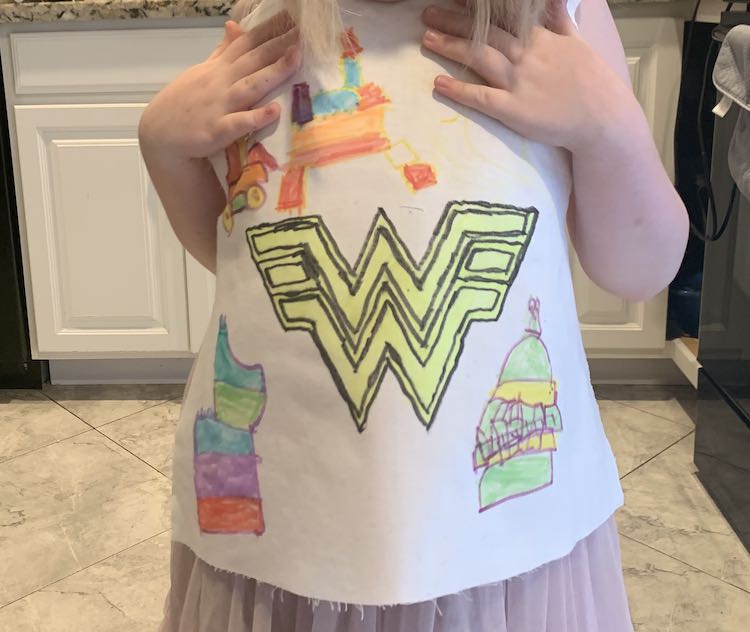 Image shows Ada standing in our kitchen holding up the white decorated front bodice piece so I could grab a photo of her with her creation.
