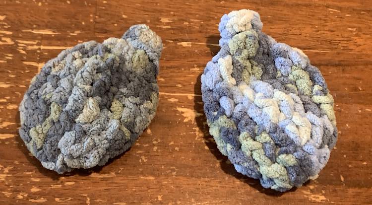 View shows two crocheted blue water balloons. The one on the left is dirty and shriveled looking while the one on the right is clean, dried, and puffy.