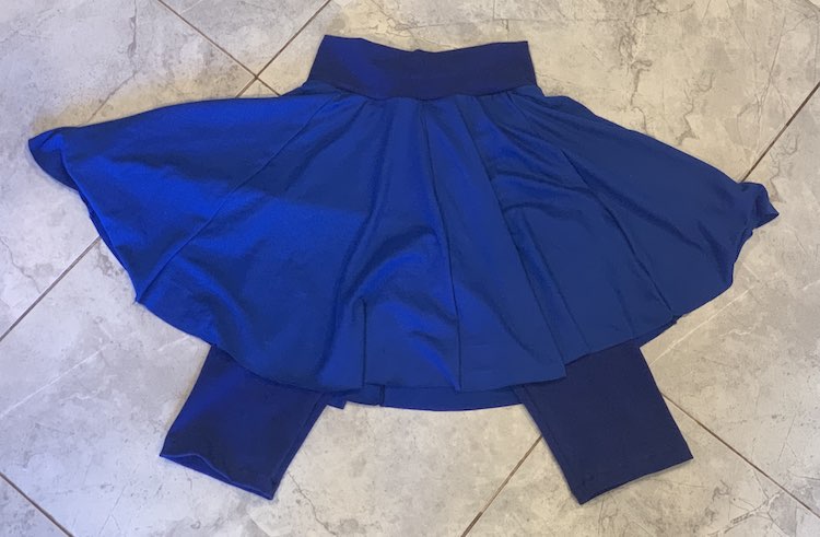 Photo is an overview of a blue skort laid out on the floor. I used a darker fabric for the leggings and waistband and a lighter fabric for the full skirt.