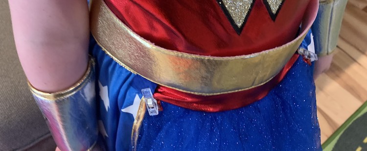 Closeup of the belt part of the dress. You can see a blue sewing clip holding the edge of the skirt overlay to the bottom of the red bodice fabric on either side. 