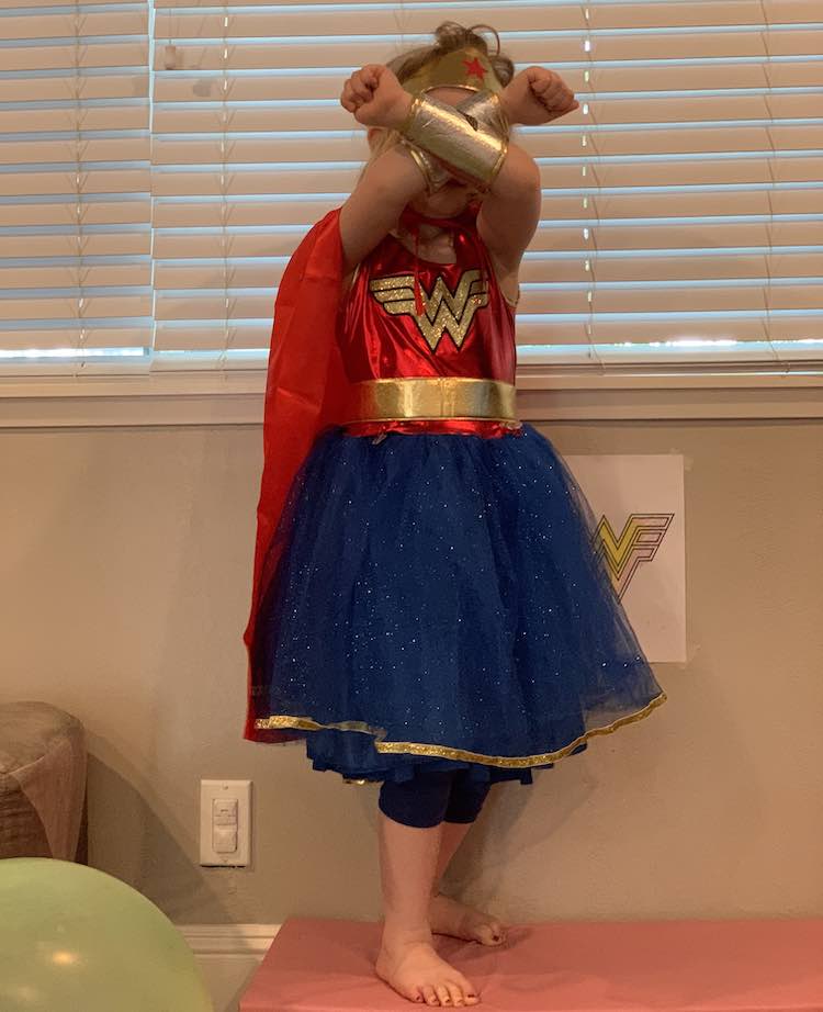 Front view of Ada in her costume including the skort and cape we added. Her arms are crossed in front of her face showing the arm guards and the tiara.