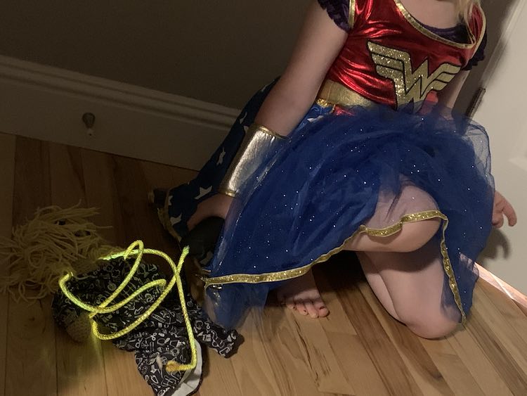 Wonder Woman crouched with her lasso of truth wrapped around her crochet doll trying to extract the truth.