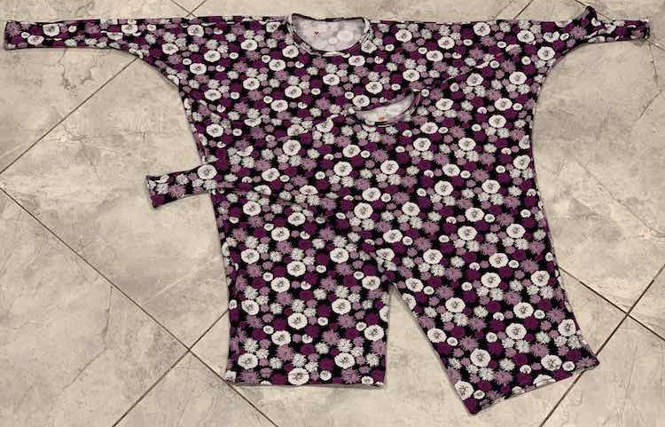 Image shows a flat lay of the two finished flowered tunics laying on the kitchen floor. Inside the neckline you can see, if you look closely, a little red or orange heart on the white-ish inside. 