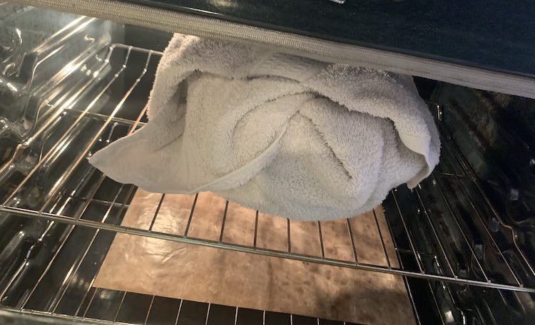 View of the wrapped Dutch oven sitting on the top shelf of my oven. The door is open to take the photo so the light is on.