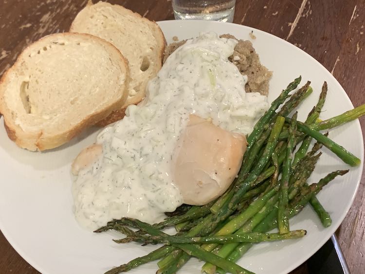 Image shows a plate with two slices of bread, quinoa and chicken coated in tzatziki, and a pile of asparagus.