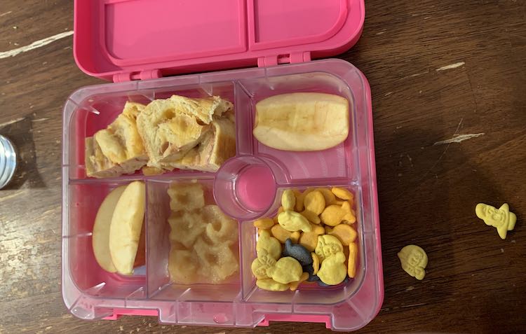 Image shows an open pink divided lunchbox. The section being shown shows star-shaped applesauce shapes. The other cubbies hold sandwich bread, apples, and a mix of cheese crackers. 