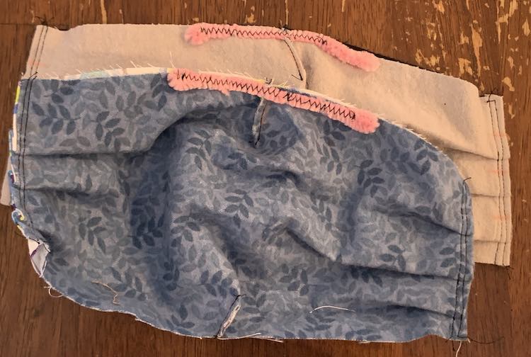 Image shows the same face masks stacked as last time although this time there's no sewing clips to be seen and the pipe cleaner is sewn down with a black zigzag stitch over it's pink fuzz.