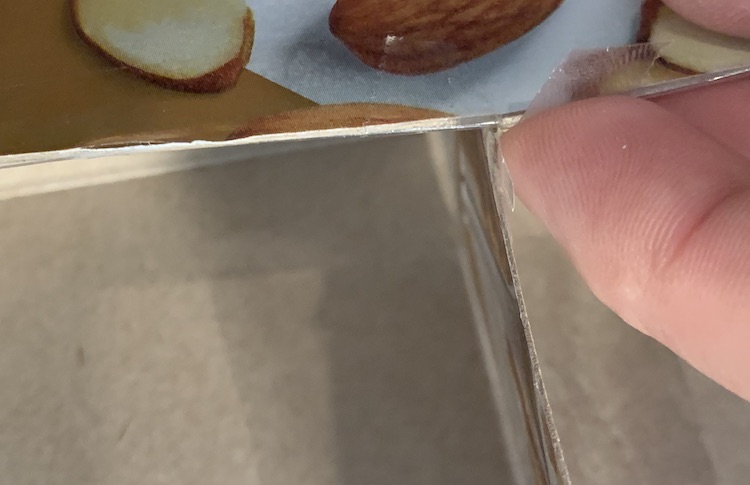 Image shows a closeup of the top of the divider showing where the strip leaves the overhang on the top of the box. There's a piece of fingerprinted tape about to be folded over by my finger. 