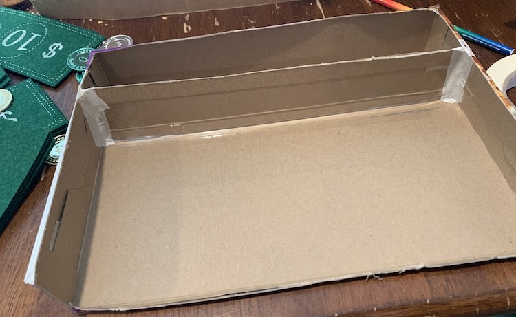 Image show a view above and to the front of the cereal box; when looking straight at it. The edges of the divider are taped down with beige tape.