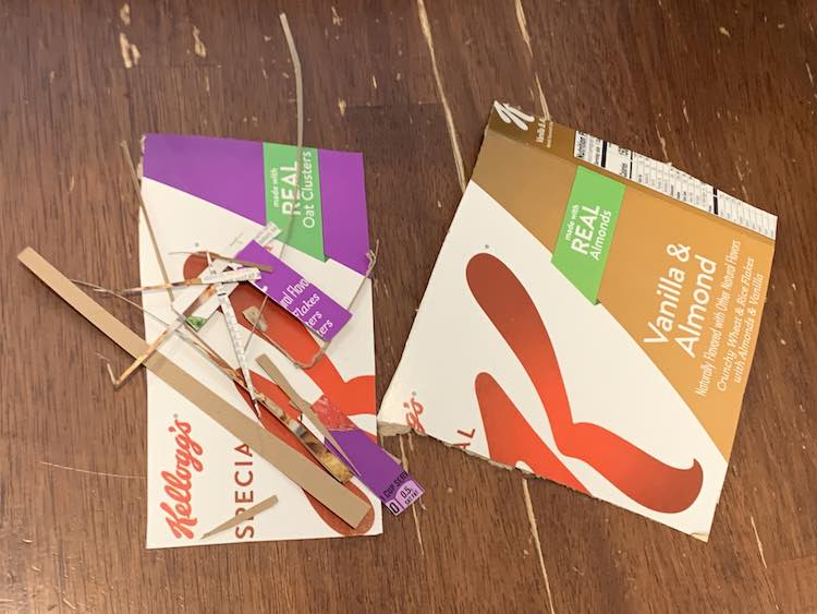 Image shows two larger pieces of cardboard and a lot of little sections, from trimming things to size, laid out on the table.