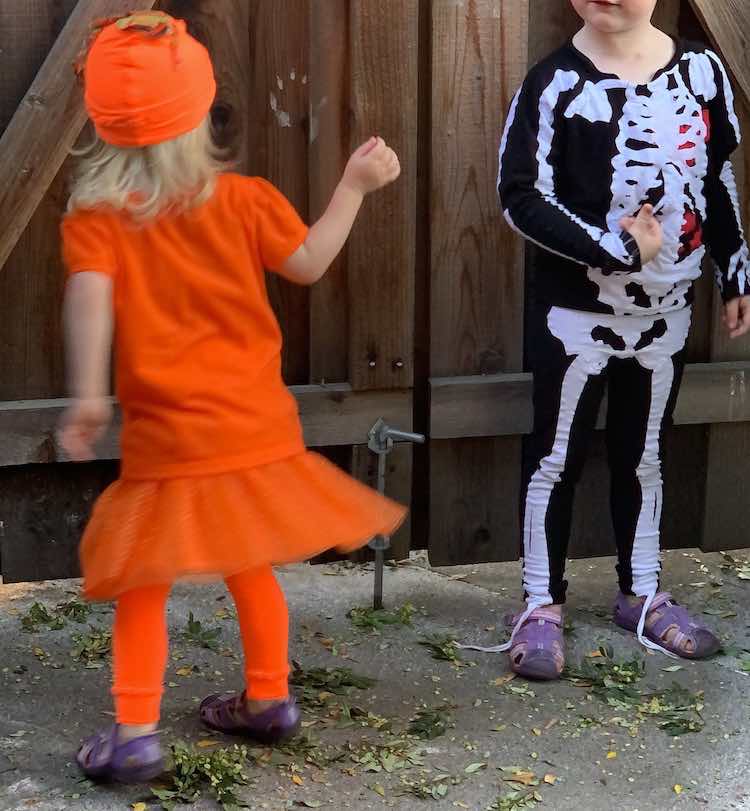 Image shows the back of Zoey's pumpkin costume as she twirls. To the right is Ada's swaying skeleton.