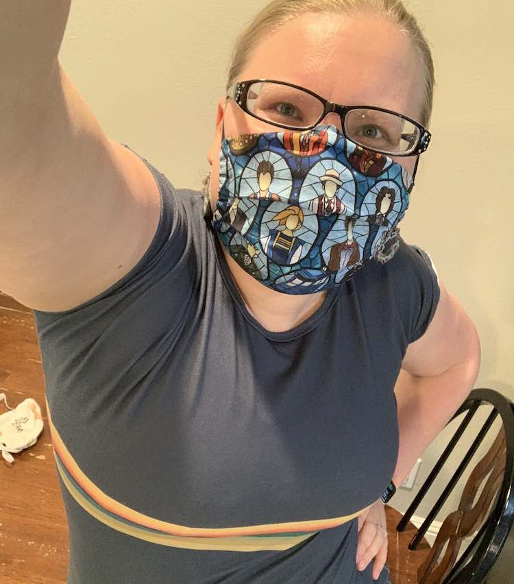 Image shows me taking a selfie looking into the camera I'm holding up with my other hand on my hip. I'm standing in front of the kitchen table wearing my new Doctor Who mask with my older Doctor Who shirt.