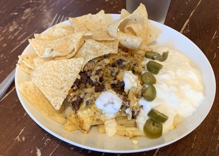 Image shows a closeup of my plate filled with the taco lasagna-ish, tortilla chips, yogurt, and a row of sliced jalapenos. 