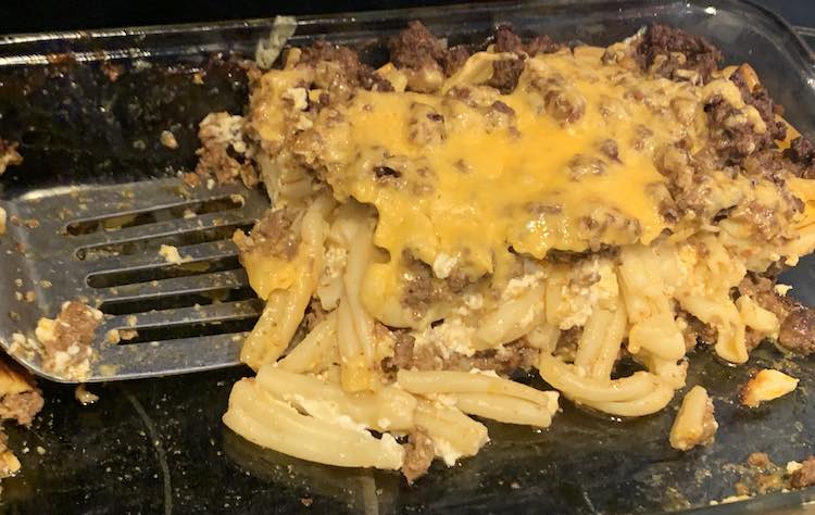 Image is a closeup of the last square of taco lasagna left in the pan with a metal flipper ready to serve it up. 