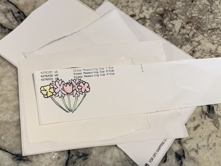 Image shows the same stack of blank stickers as the previous image. This time the flowers and stems have been colored in with pencil crayon. 