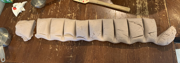 Photo shows a tube of light lavender playdough cut into eleven slices. 