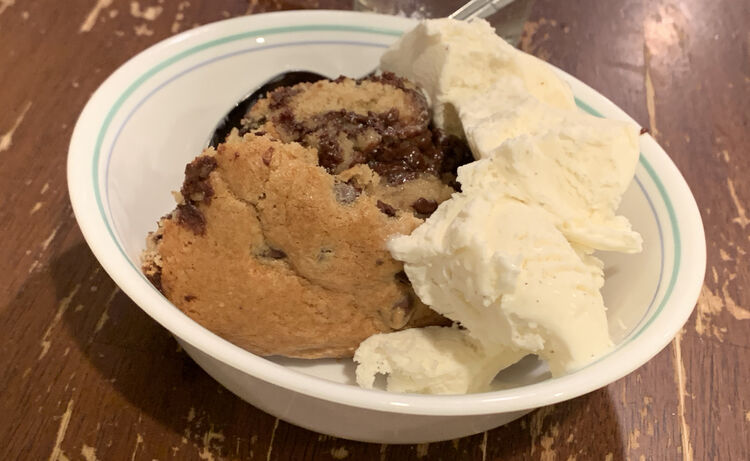 Image shows a blue lined white bowl with a slice of hot chocolate chip cookie and