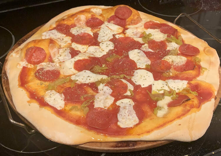 Image shows a browned crust pizza covering most of a pizza stone. It's coated in amazingly heated ingredients.