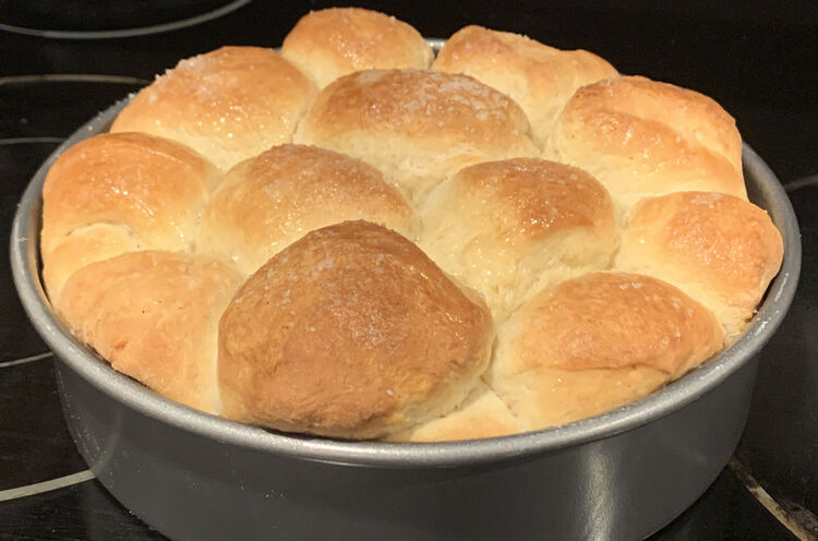 Image shows a metal cake pan filled with browned and rounded buns all baked together.