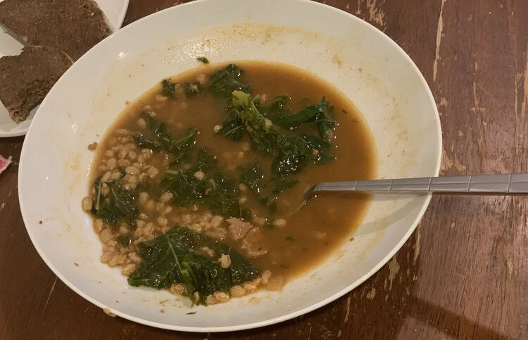 Image shows a bowl half filled with the brown soup with greens. You can see how high the soup used to be by the markings on the side.