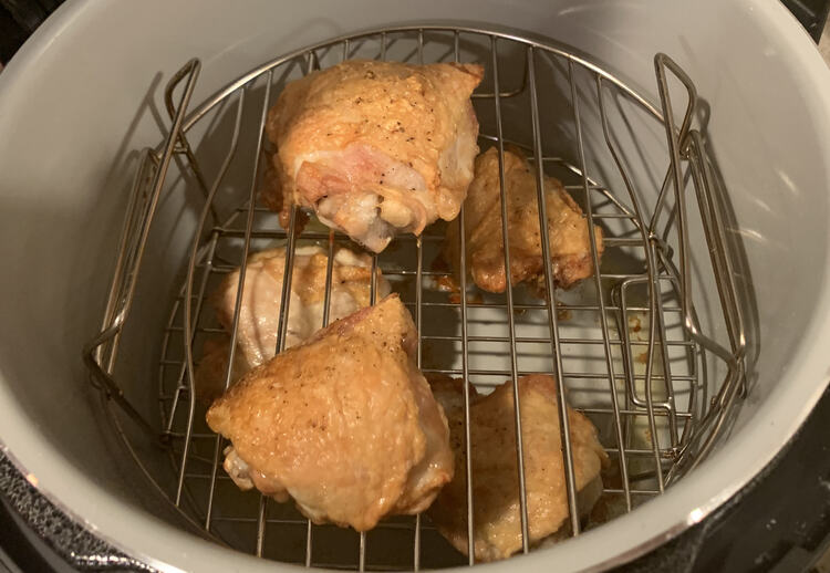 Image shows five chicken thighs laid out over two wire trays in the Ninja Foodi. 