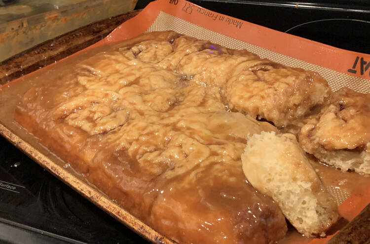 Image shows the damp and wrinkled looking cinnamon buns laid out on a Silpat lined baking sheet. 