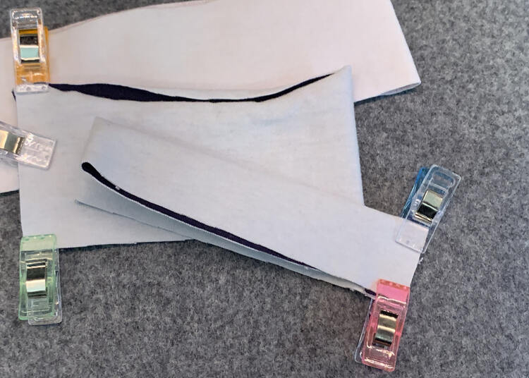 Image shows the properly folded cuff with a pink and blue clip holding it tightly together. In the background are two bands that haven't been folded enough yet. 