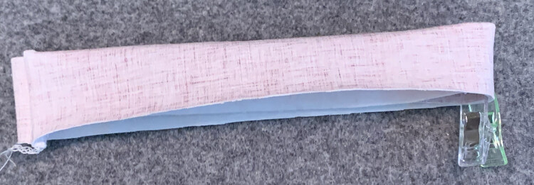 Image shows the pink band laid flat so the seam is on the one side and the clipped halfway point is on the other. 